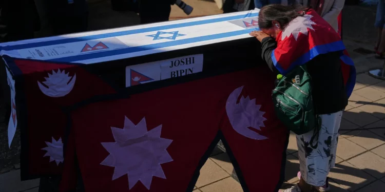 Familiares y amigos del ciudadano nepalí Bipin Joshi, quien fue tomado como rehén por Hamás en Gaza, junto a su ataúd durante una ceremonia de despedida antes de que su cuerpo sea trasladado a Nepal para su entierro en el Aeropuerto Ben Gurion, el 19 de octubre de 2025. (AP/Ariel Schalit)