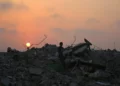 Un palestino desplazado se encuentra de pie sobre los escombros de los edificios destruidos en la guerra de Gaza, mientras el sol se pone sobre el campamento de Bureij en el centro de la Franja de Gaza el 10 de noviembre de 2025 (Eyad Baba / AFP).