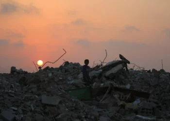 Un palestino desplazado se encuentra de pie sobre los escombros de los edificios destruidos en la guerra de Gaza, mientras el sol se pone sobre el campamento de Bureij en el centro de la Franja de Gaza el 10 de noviembre de 2025 (Eyad Baba / AFP).