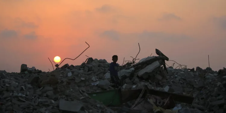 Un palestino desplazado se encuentra de pie sobre los escombros de los edificios destruidos en la guerra de Gaza, mientras el sol se pone sobre el campamento de Bureij en el centro de la Franja de Gaza el 10 de noviembre de 2025 (Eyad Baba / AFP).
