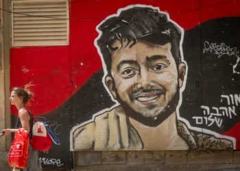 Personas caminan junto a un mural del rehén asesinado Hersh Goldberg-Polin en el centro de Jerusalén, 18 de agosto de 2025. (Foto de Chaim Goldberg/Flash90)
