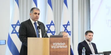 El ministro de Inmigración y Absorción, Ofir Sofer, habla mientras el ministro de Finanzas, Bezalel Smotrich, escucha en una ceremonia en la oficina de Nefesh B'Nefesh en Jerusalén el 6 de noviembre de 2025 (GPO/Sivan Shahor)