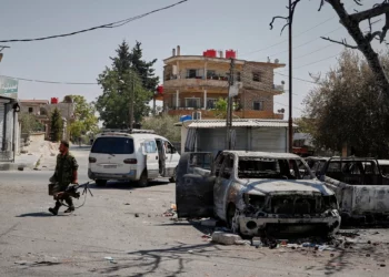 Un miliciano druso que porta una ametralladora pasa junto a un automóvil calcinado tras los enfrentamientos sectarios en la ciudad de Sweida, Siria, de mayoría drusa, el 25 de julio de 2025. (Foto AP/Omar Sanadiki)