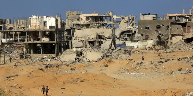 Palestinos caminan entre edificios destruidos en la zona oriental de Khan Younis, en el sur de la Franja de Gaza, el 12 de noviembre de 2025. (Abed Rahim Khatib/Flash90)