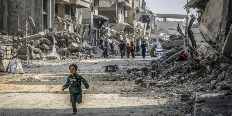 Un niño palestino corre junto a edificios destruidos en la guerra de Gaza, en Jan Yunis, sur de la Franja de Gaza, 6 de noviembre de 2025. (Abed Rahim Khatib/Flash90)