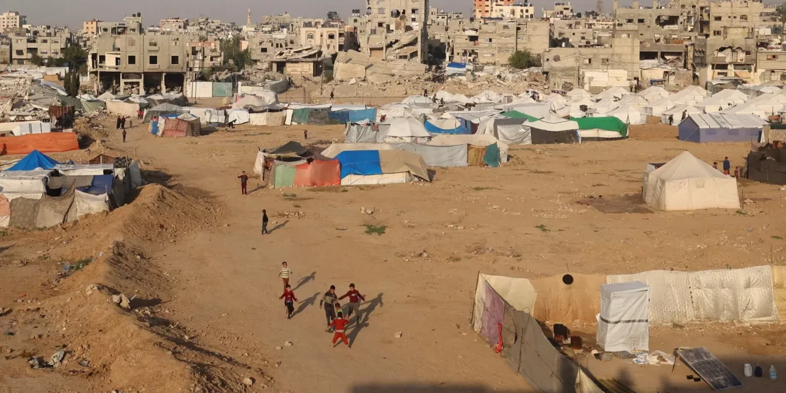 Niños juegan cerca de refugios y tiendas de campaña en el campamento de Bureij, en el centro de la Franja de Gaza, el 18 de noviembre de 2025. (Eyad Baba / AFP)