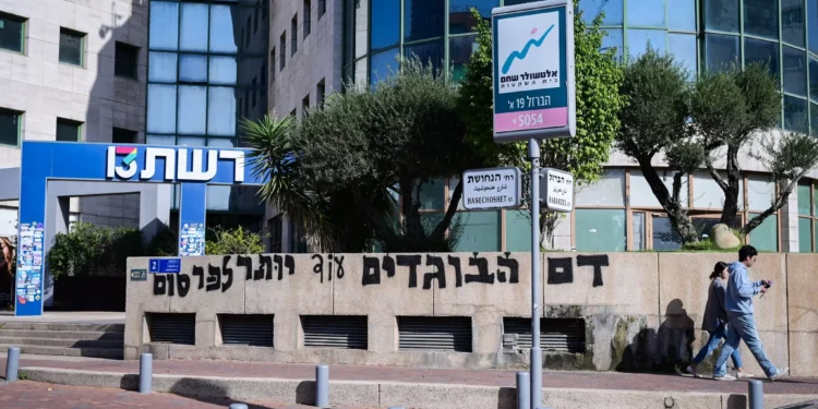 Vista de grafitis pintados durante la noche frente a las oficinas del Canal 13 en Tel Aviv, 19 de noviembre de 2025 (Avshalom Sassoni/Flash90)