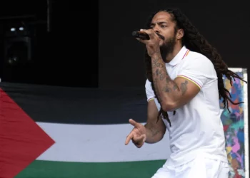Con una bandera palestina de fondo, Bobby Vylan, del dúo británico Bob Vylan, actúa en el escenario West Holts el cuarto día del festival de Glastonbury en Worthy Farm, en el pueblo de Pilton, Somerset, suroeste de Inglaterra, el 28 de junio de 2025. (Oli SCARFF / AFP)