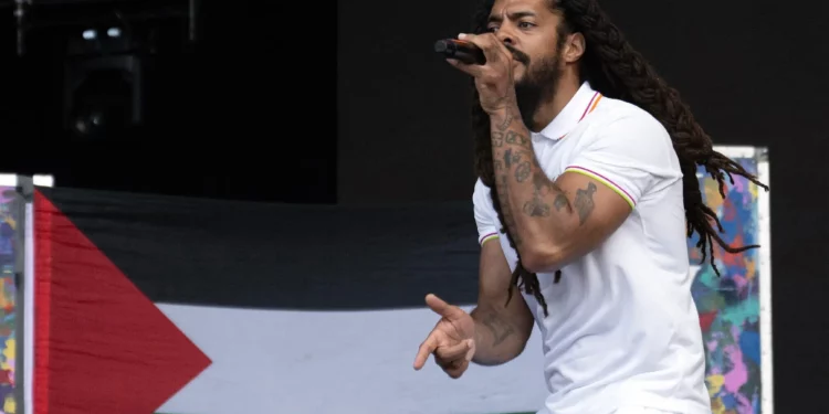 Con una bandera palestina de fondo, Bobby Vylan, del dúo británico Bob Vylan, actúa en el escenario West Holts el cuarto día del festival de Glastonbury en Worthy Farm, en el pueblo de Pilton, Somerset, suroeste de Inglaterra, el 28 de junio de 2025. (Oli SCARFF / AFP)