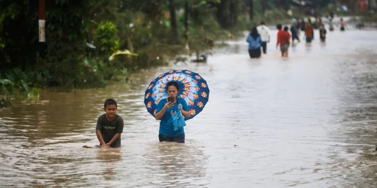 La gente camina a través del agua en una calle inundada en Medan, Sumatra del Norte, Indonesia, el 27 de noviembre de 2025. (Foto AP/Binsar Bakkara)