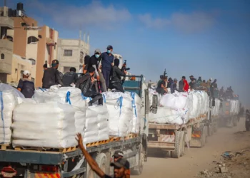 Imagen ilustrativa: Palestinos armados sentados en camiones que transportan ayuda humanitaria cerca del paso fronterizo de Zikim entre Israel y Beit Lahia, en el norte de la Franja de Gaza, 25 de junio de 2025. (Ali Qariqa/Flash90)