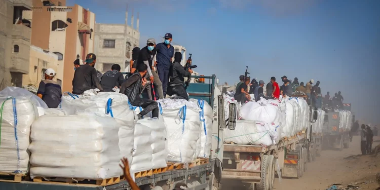 Imagen ilustrativa: Palestinos armados sentados en camiones que transportan ayuda humanitaria cerca del paso fronterizo de Zikim entre Israel y Beit Lahia, en el norte de la Franja de Gaza, 25 de junio de 2025. (Ali Qariqa/Flash90)
