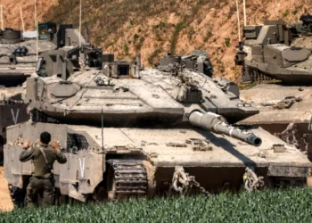 Un soldado del ejército israelí hace señas al conductor de un tanque de batalla Merkava que intenta estacionarse en una posición en el sur de Israel, a lo largo de la Franja de Gaza, el 18 de marzo de 2025. (Menahem Kahana / AFP)