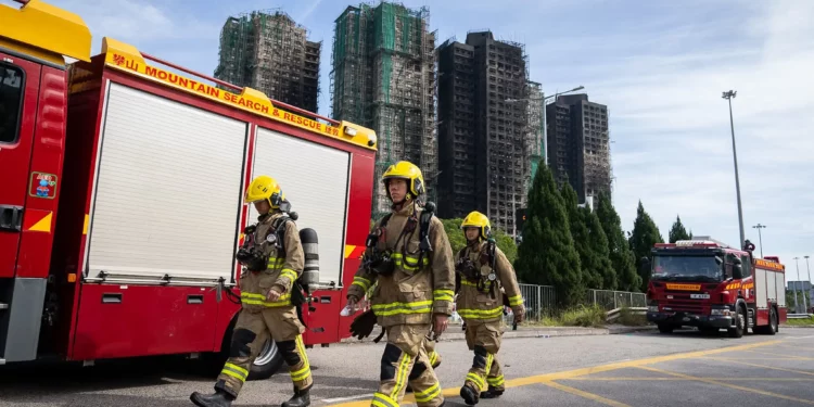 Los bomberos pasan junto a la escena del incendio en Wang Fuk Court, una urbanización del distrito de Tai Po, en los Nuevos Territorios de Hong Kong, el 28 de noviembre de 2025. (Foto AP/Chan Long Hei)