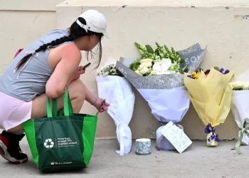 Un doliente coloca flores tras la limpieza de los tributos florales fuera del Pabellón Bondi, después de siete días de luto, una semana después del atentado terrorista en Bondi Beach contra un evento de Janucá, en Sídney el 22 de diciembre de 2025. (Saeed KHAN / AFP)