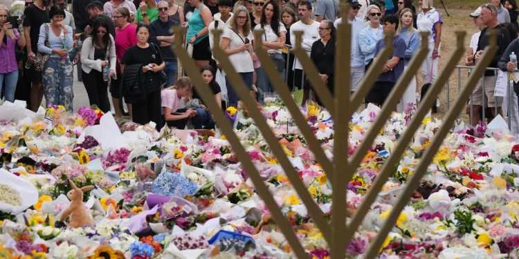 Una menorá de Janucá se encuentra junto a un tributo floral mientras la gente se reúne para rendir homenaje cerca del Pabellón Bondi en Bondi Beach el 16 de diciembre de 2025, tras el mortal tiroteo terrorista dirigido a un evento de Janucá en Sídney, Australia. (AP/Mark Baker)