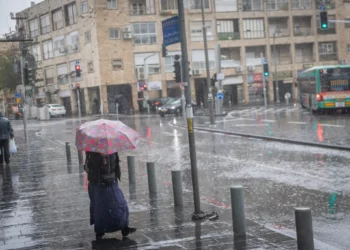 La gente camina por las calles inundadas de Jerusalén mientras la tormenta Byron azota Israel, el 11 de diciembre de 2025. (Chaim Goldberg/FLASH90)
