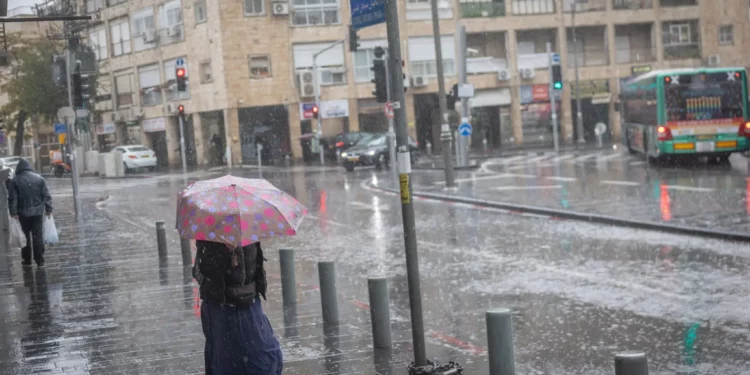La gente camina por las calles inundadas de Jerusalén mientras la tormenta Byron azota Israel, el 11 de diciembre de 2025. (Chaim Goldberg/FLASH90)
