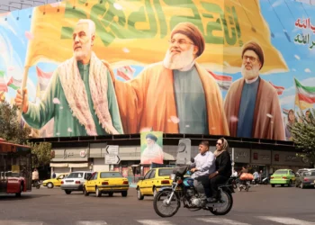 Iraníes viajan en motocicleta frente a una valla publicitaria que representa a los líderes libaneses asesinados de Hezbolá, Hassan Nasrallah (centro) y su sucesor, Hashem Safieddine (derecha), así como al difunto general iraní Qasem Soleimani, en Teherán el 28 de septiembre de 2025. (ATTA KENARE / AFP)