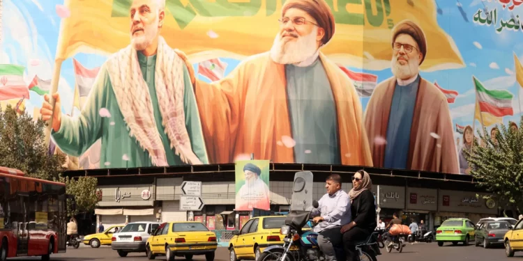 Iraníes viajan en motocicleta frente a una valla publicitaria que representa a los líderes libaneses asesinados de Hezbolá, Hassan Nasrallah (centro) y su sucesor, Hashem Safieddine (derecha), así como al difunto general iraní Qasem Soleimani, en Teherán el 28 de septiembre de 2025. (ATTA KENARE / AFP)