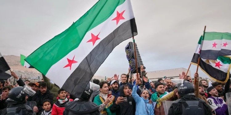 Sirios se alinean en las calles a la espera de un desfile del nuevo ejército sirio que conmemora el primer aniversario del derrocamiento del régimen de Bashar al-Assad en Damasco, Siria, el 8 de diciembre de 2025. (Foto AP/Hussein Malla)