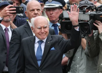 John Howard (C), ex primer ministro de Australia, saluda a la multitud después de depositar flores fuera del Bondi Pavilion en Sídney el 16 de diciembre de 2025, para honrar a las víctimas del ataque terrorista de Hanukkah (DAVID GRAY / AFP)