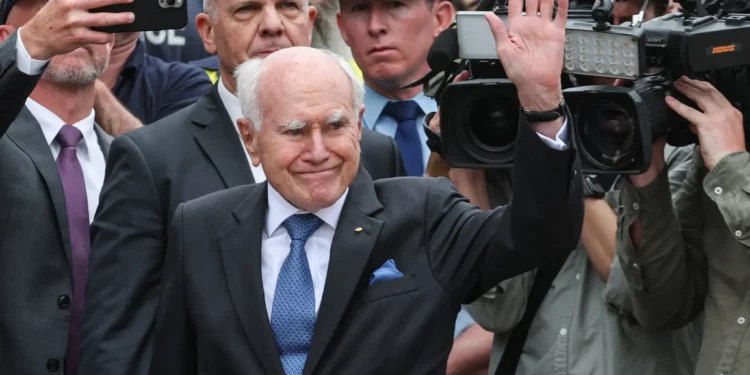 John Howard (C), ex primer ministro de Australia, saluda a la multitud después de depositar flores fuera del Bondi Pavilion en Sídney el 16 de diciembre de 2025, para honrar a las víctimas del ataque terrorista de Hanukkah (DAVID GRAY / AFP)