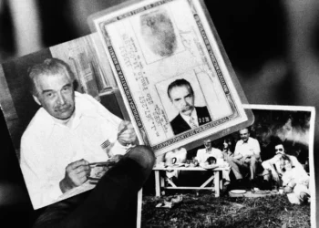 Un agente de la policía federal sostiene dos fotos y el documento de identidad encontrados en la casa donde vivió el presunto criminal de guerra nazi Josef Mengele, el 7 de junio de 1985. La foto de la izquierda muestra a Mengele comiendo. La foto de la derecha muestra a Mengele durante un picnic con amigos y en el centro se encuentra el documento de identidad. (Foto AP)