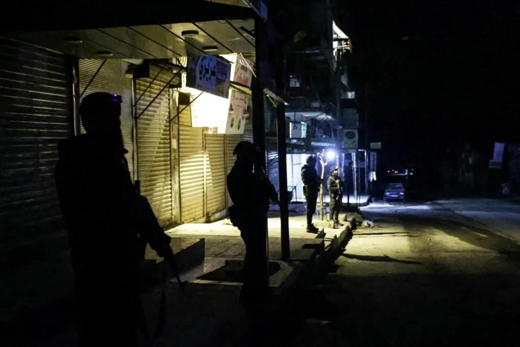 Miembros de los Cascos Blancos, un grupo voluntario de defensa civil, ayudan a una anciana a huir de los barrios de Sheikh Maqsoud y Achrafieh en Alepo, Siria, el jueves 8 de enero de 2026, tras los enfrentamientos que estallaron el martes entre las fuerzas gubernamentales sirias y los combatientes kurdos. (AP/Ghaith Alsayed)