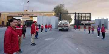 Miembros de la Media Luna Roja Egipcia supervisan un camión que transporta ayuda humanitaria al entrar por el paso fronterizo de Rafah entre Egipto y la Franja de Gaza, tras el acuerdo de alto el fuego entre Israel y Hamás, el 12 de octubre de 2025. (AP Photo/Mohamed Arafat)