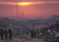Gazatíes caminan entre las ruinas de edificios destruidos mientras el sol se pone sobre la ciudad de Gaza, el 4 de enero de 2026. (AP/Jehad Alshrafi)