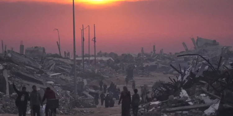 Palestinos caminan entre las ruinas de edificios destruidos mientras el sol se pone sobre la ciudad de Gaza, el 4 de enero de 2026. (Foto AP/Jehad Alshrafi)