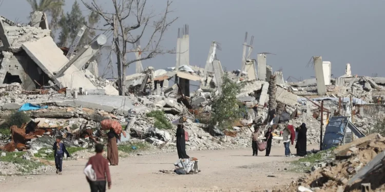 Mujeres y niños recogen leña de casas destruidas en la zona de Mughraqa, 5 de enero de 2026 (Ali Hassan/Flash90)