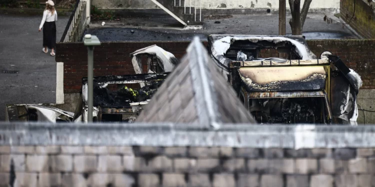 Una mujer camina junto a unas ambulancias dañadas y calcinadas (a la derecha) en la zona de Golders Green, al norte de Londres, el 23 de marzo de 2026, después de que durante la noche se incendiaran unas ambulancias de voluntarios gestionadas por una organización judía. (Foto de Henry NICHOLLS / AFP)