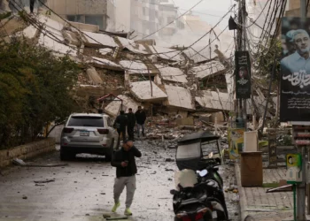 Unas personas caminan por una calle bloqueada por los escombros de un edificio destruido en un ataque aéreo israelí en Dahiyeh, en los suburbios del sur de Beirut, Líbano, el 14 de marzo de 2026. (Foto AP/Hassan Ammar)