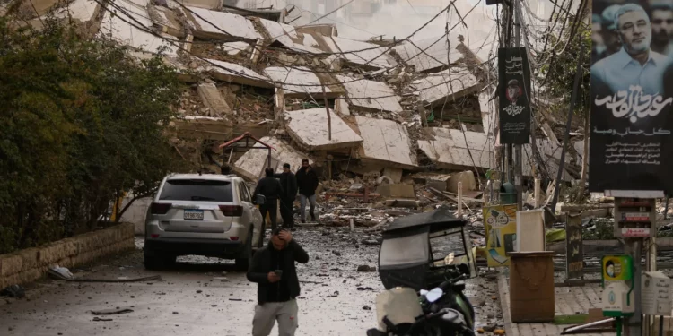 Unas personas caminan por una calle bloqueada por los escombros de un edificio destruido en un ataque aéreo israelí en Dahiyeh, en los suburbios del sur de Beirut, Líbano, el 14 de marzo de 2026. (Foto AP/Hassan Ammar)