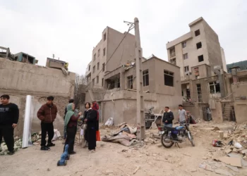 Los iraníes se reúnen frente a edificios destruidos tras un ataque militar contra la capital iraní, Teherán, el 15 de marzo de 2026. (Atta KENARE / AFP) /