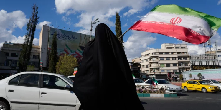 Una mujer ondea una bandera iraní durante una manifestación en apoyo al Gobierno en la plaza Enqelab-e-Eslami, o de la Revolución Islámica, en el centro de Teherán, el 30 de marzo de 2026. (Foto AP/Vahid Salemi)