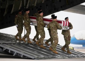 Un equipo de transporte del Ejército de los Estados Unidos traslada una caja cubierta con la bandera con los restos mortales del sargento Declan Coady, de 20 años, de West Des Moines, Iowa, que murió en un ataque con drones en un centro de mando en Kuwait después de que Estados Unidos e Israel lanzaran su campaña militar contra Irán, pasando junto al presidente Donald Trump y la primera dama Melania Trump durante el regreso de las víctimas, el sábado 7 de marzo de 2026, en la base aérea de Dover, Delaware. (Foto AP/Mark Schiefelbein)