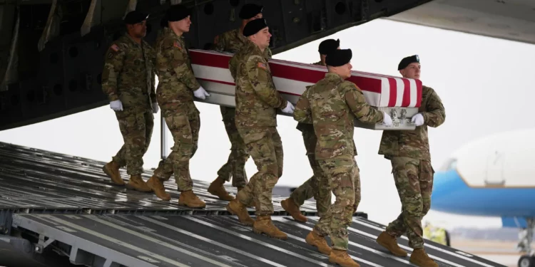 Un equipo de transporte del Ejército de los Estados Unidos traslada una caja cubierta con la bandera con los restos mortales del sargento Declan Coady, de 20 años, de West Des Moines, Iowa, que murió en un ataque con drones en un centro de mando en Kuwait después de que Estados Unidos e Israel lanzaran su campaña militar contra Irán, pasando junto al presidente Donald Trump y la primera dama Melania Trump durante el regreso de las víctimas, el sábado 7 de marzo de 2026, en la base aérea de Dover, Delaware. (Foto AP/Mark Schiefelbein)
