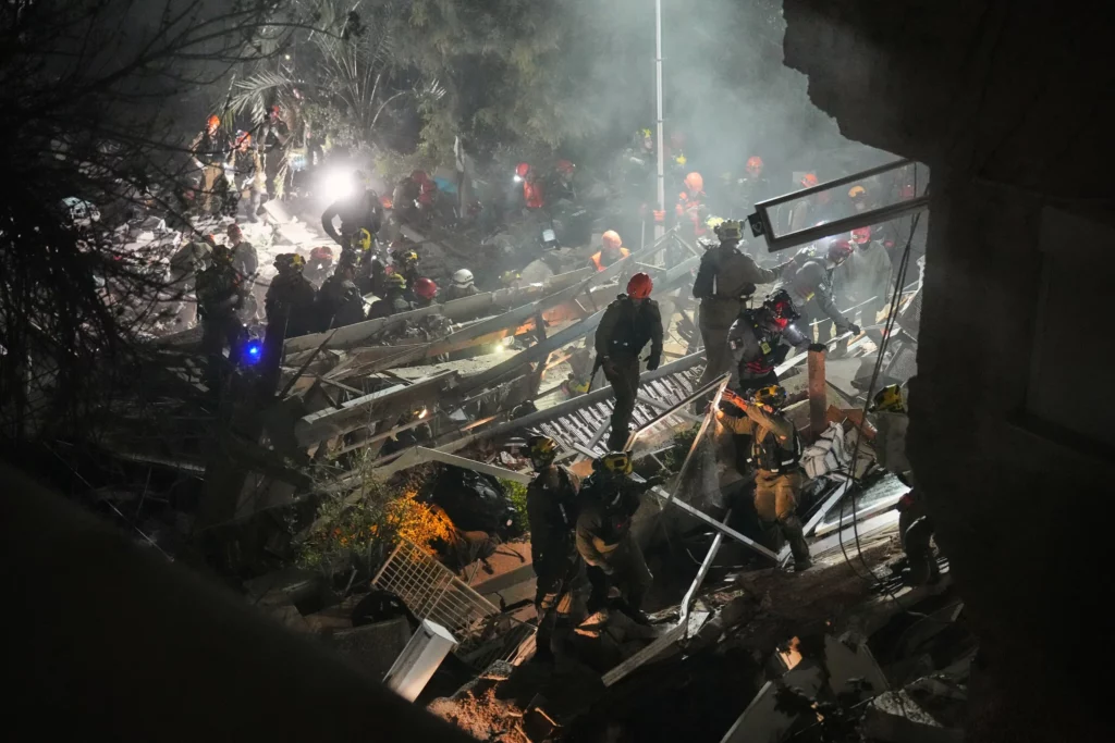 Las fuerzas de seguridad y los equipos de rescate israelíes trabajan entre los escombros de un edificio residencial alcanzado por un misil iraní en Haifa, el 5 de abril de 2026. (Foto AP/Ariel Schalit)