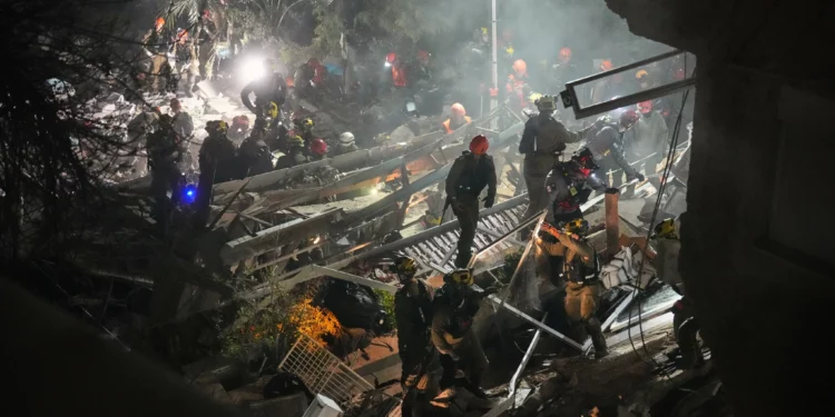 Las fuerzas de seguridad y los equipos de rescate israelíes trabajan entre los escombros de un edificio residencial alcanzado por un misil iraní en Haifa, el 5 de abril de 2026. (Foto AP/Ariel Schalit)