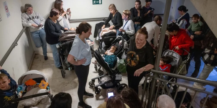Los israelíes se refugian en un refugio antiaéreo público mientras una sirena avisa de la llegada de misiles lanzados desde Irán, 31 de marzo de 2026. (Miriam Alster/Flash90)