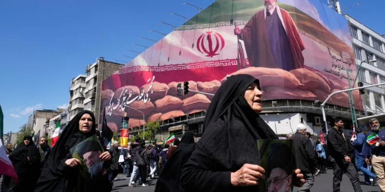 Unas mujeres pasan junto a una valla publicitaria en la que aparece el líder supremo de Irán, Mojtaba Jamenei, mientras los partidarios del Gobierno se reúnen para conmemorar el 40.º día desde el asesinato de su padre, el líder supremo Ayatolá Alí Jamenei, en Teherán, Irán, el 9 de abril de 2026. (Foto AP/Vahid Salemi)