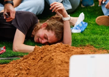 Roee, la viuda del mayor (en la reserva) Itamar Sapir, yace junto a su tumba durante su funeral en el cementerio militar de Ra'anana el 20 de mayo de 2026. (Tal Gal/Flash90)