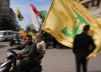 Unos hombres circulan en scooter mientras ondean una bandera de Hezbolá durante una pequeña concentración en Dahiyeh, en los suburbios del sur de Beirut (Líbano), el 25 de abril de 2026. (Foto AP/Hassan Ammar)
