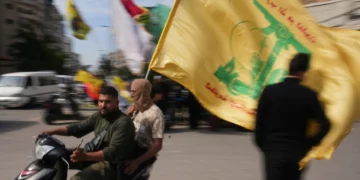 Unos hombres circulan en scooter mientras ondean una bandera de Hezbolá durante una pequeña concentración en Dahiyeh, en los suburbios del sur de Beirut (Líbano), el 25 de abril de 2026. (Foto AP/Hassan Ammar)