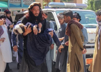 Un hombre lleva a una niña herida al hospital para que reciba atención médica tras el vuelco de un camión que transportaba a familias afganas en Jalalabad, Afganistán, el 30 de mayo de 2026. (Aimal Zahir / AFP)