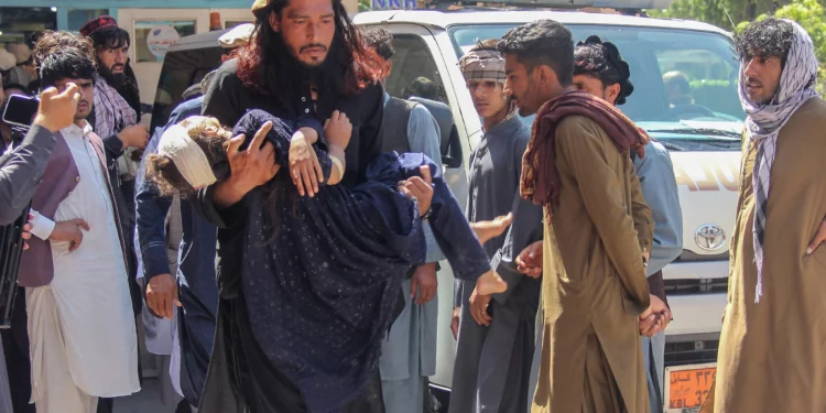 Un hombre lleva a una niña herida al hospital para que reciba atención médica tras el vuelco de un camión que transportaba a familias afganas en Jalalabad, Afganistán, el 30 de mayo de 2026. (Aimal Zahir / AFP)
