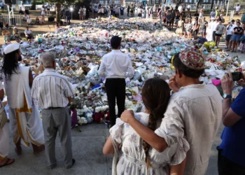 Un rabino (en el centro) pronuncia un sermón mientras los dolientes se reúnen frente a los homenajes depositados en memoria de las víctimas del atentado terrorista perpetrado durante una celebración de Jánuca en Bondi Beach, Sídney, el 20 de diciembre de 2025. (David Gray/AFP)